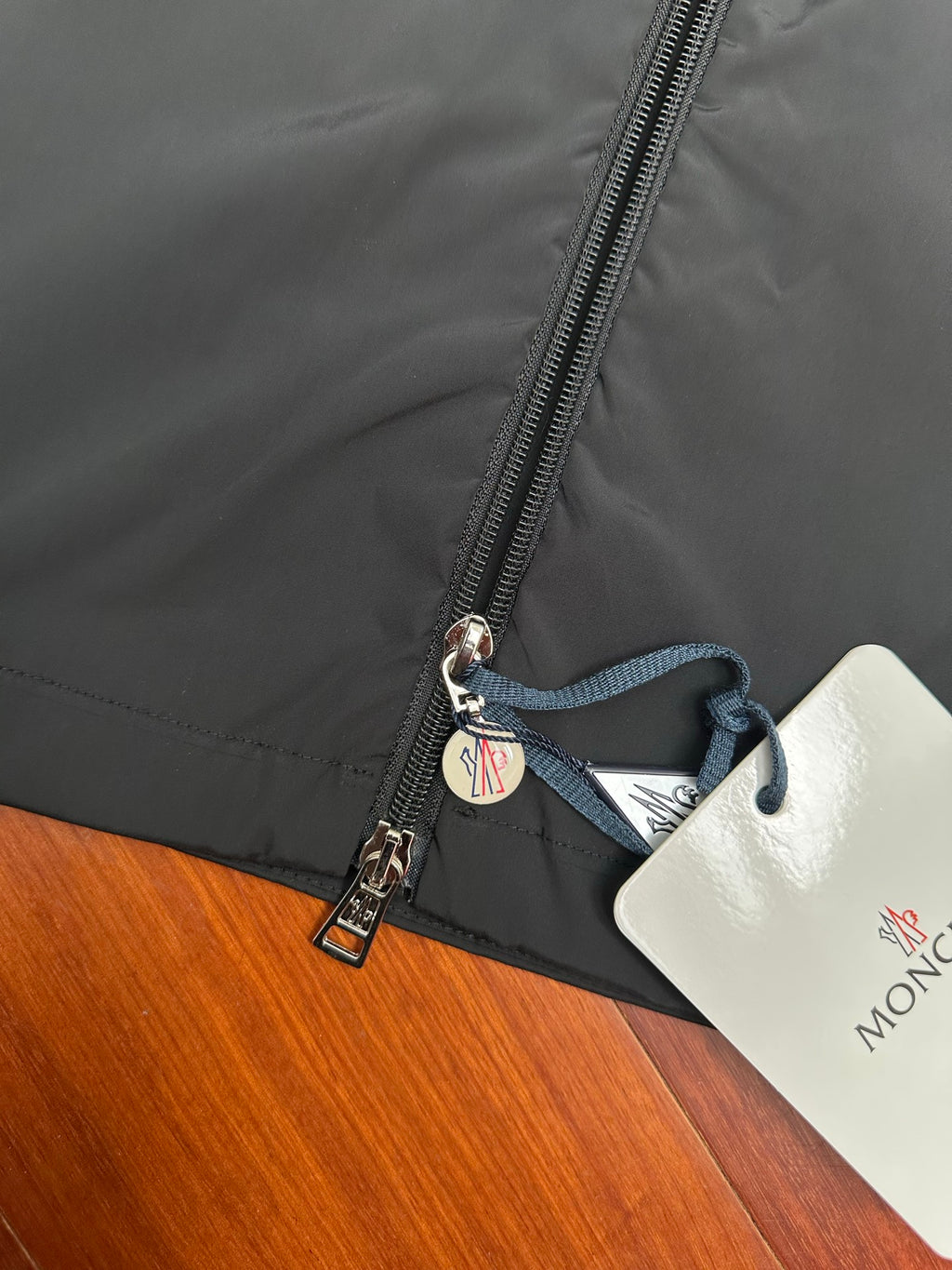 Moncler long jacket zipper with branded pull tab and blue drawstring tag
