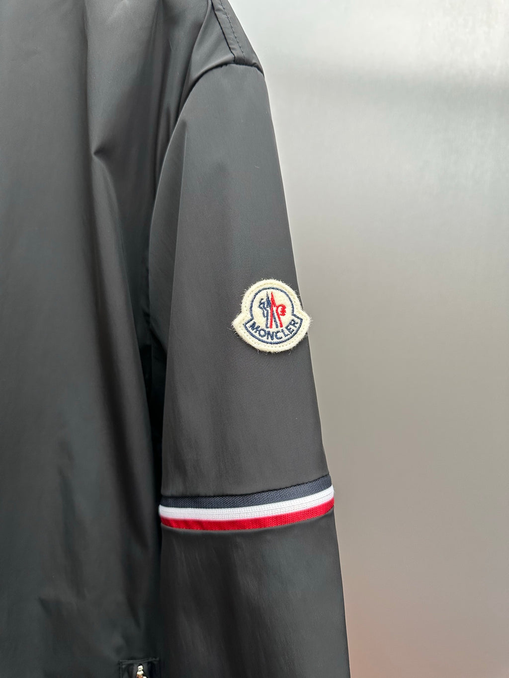 Moncler long jacket sleeve with circular logo patch and red-white-blue stripe band