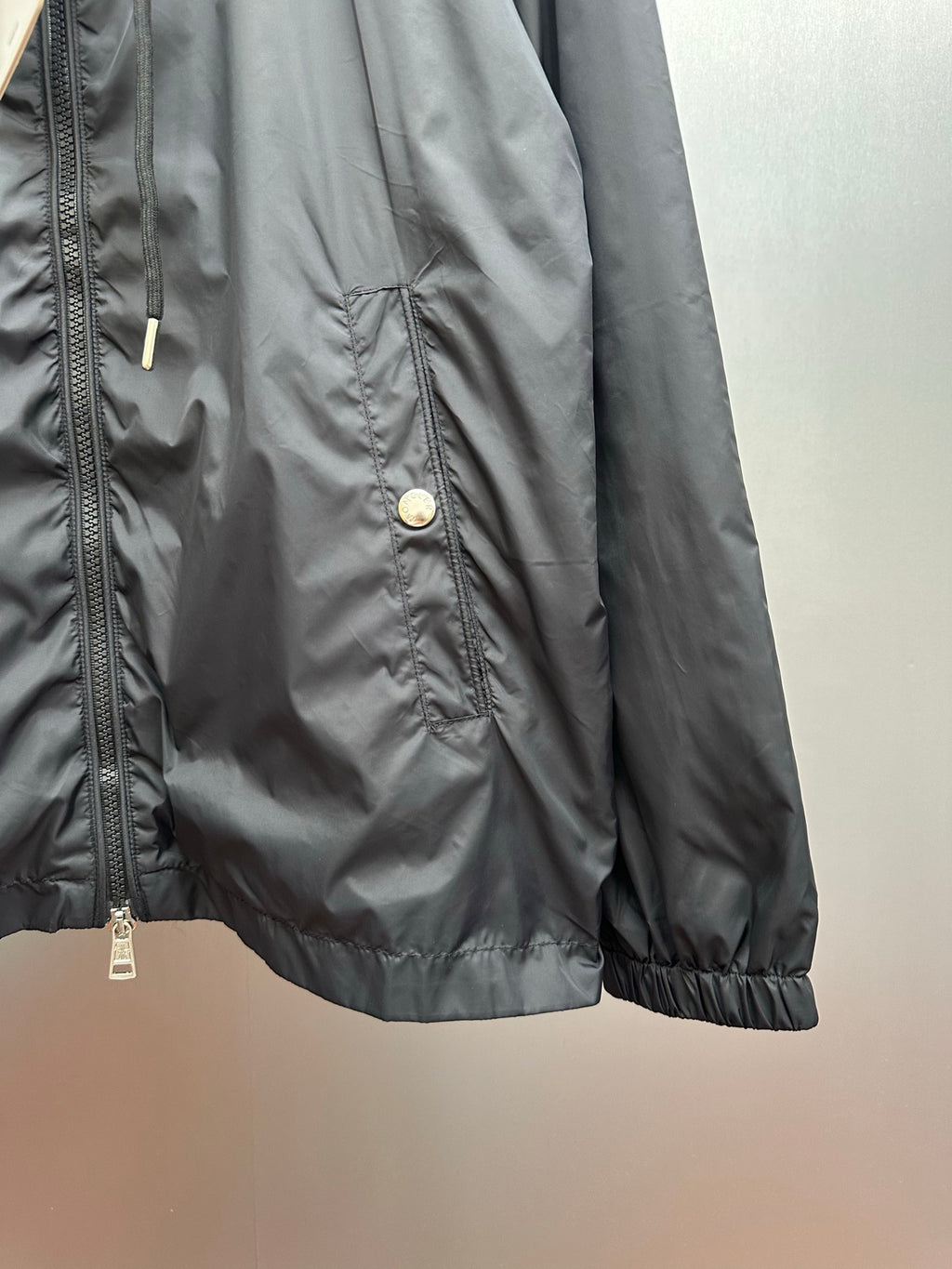 Moncler long black jacket side detail with front zipper and snap pocket