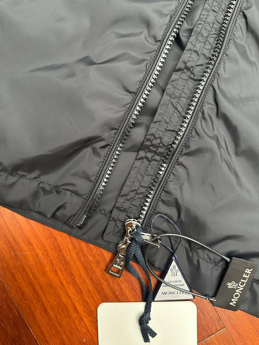 Moncler long black jacket close-up of silver zipper and hood drawcord