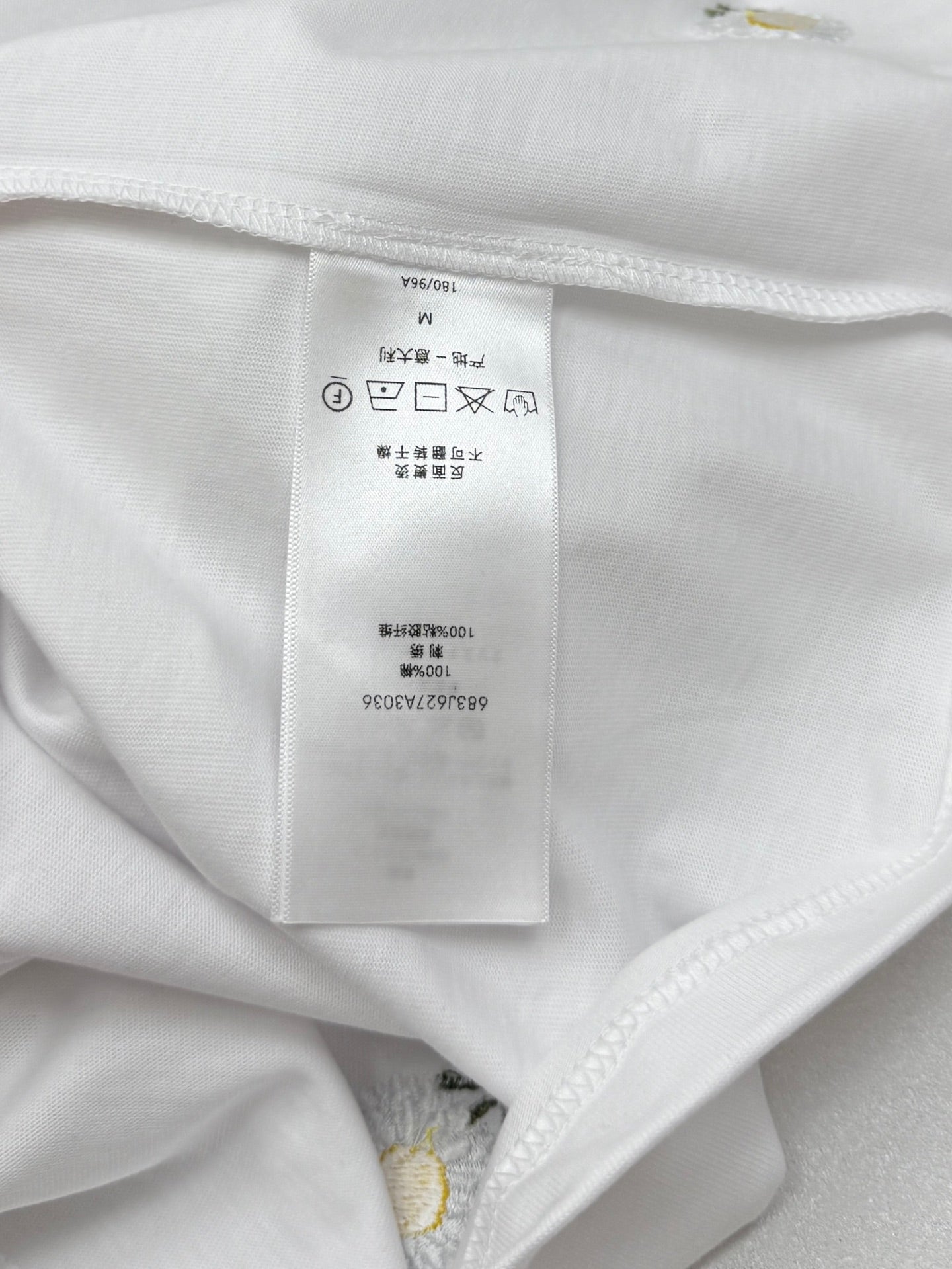 Inside collar seam with size and care tag on white T-shirt