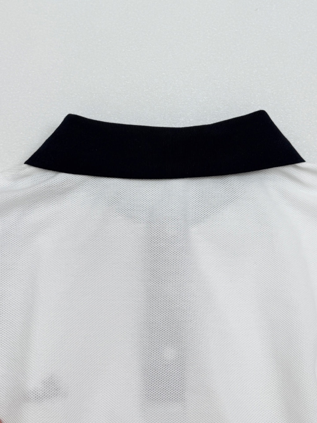 Moncler polo neckline with black collar band on white fabric
