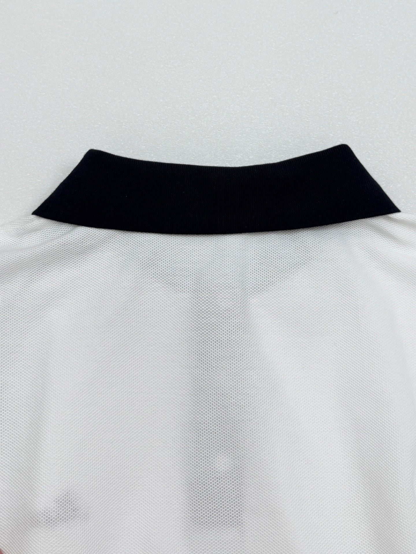 Moncler polo neckline with black collar band on white fabric