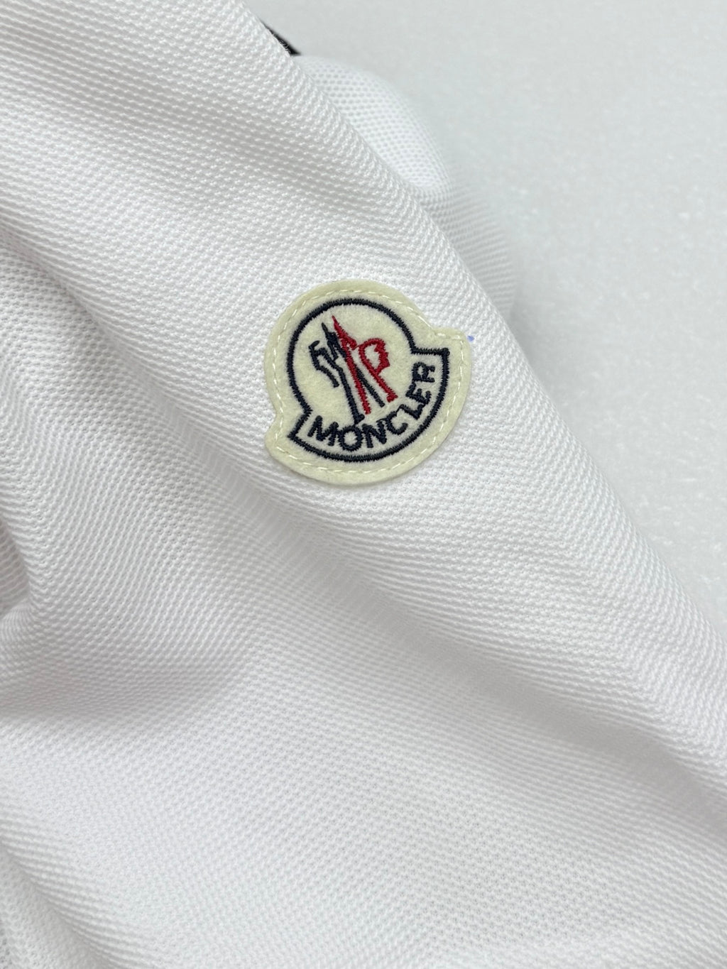 Moncler round logo patch on white polo sleeve