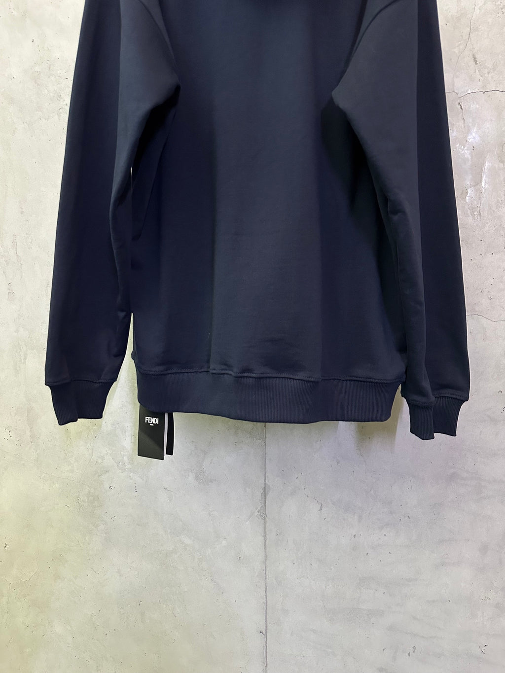 Navy hoodie back view with cuffs, kangaroo pocket, and size tag