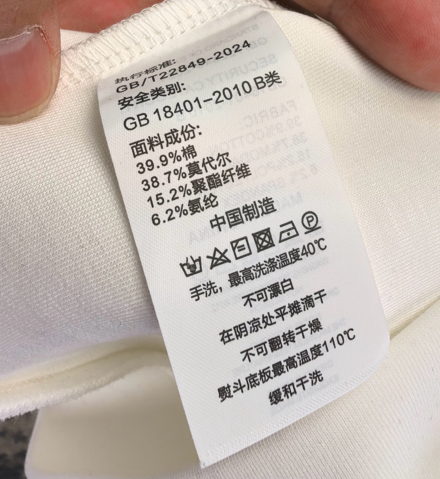 White fabric care label attached to sweatshirt material
