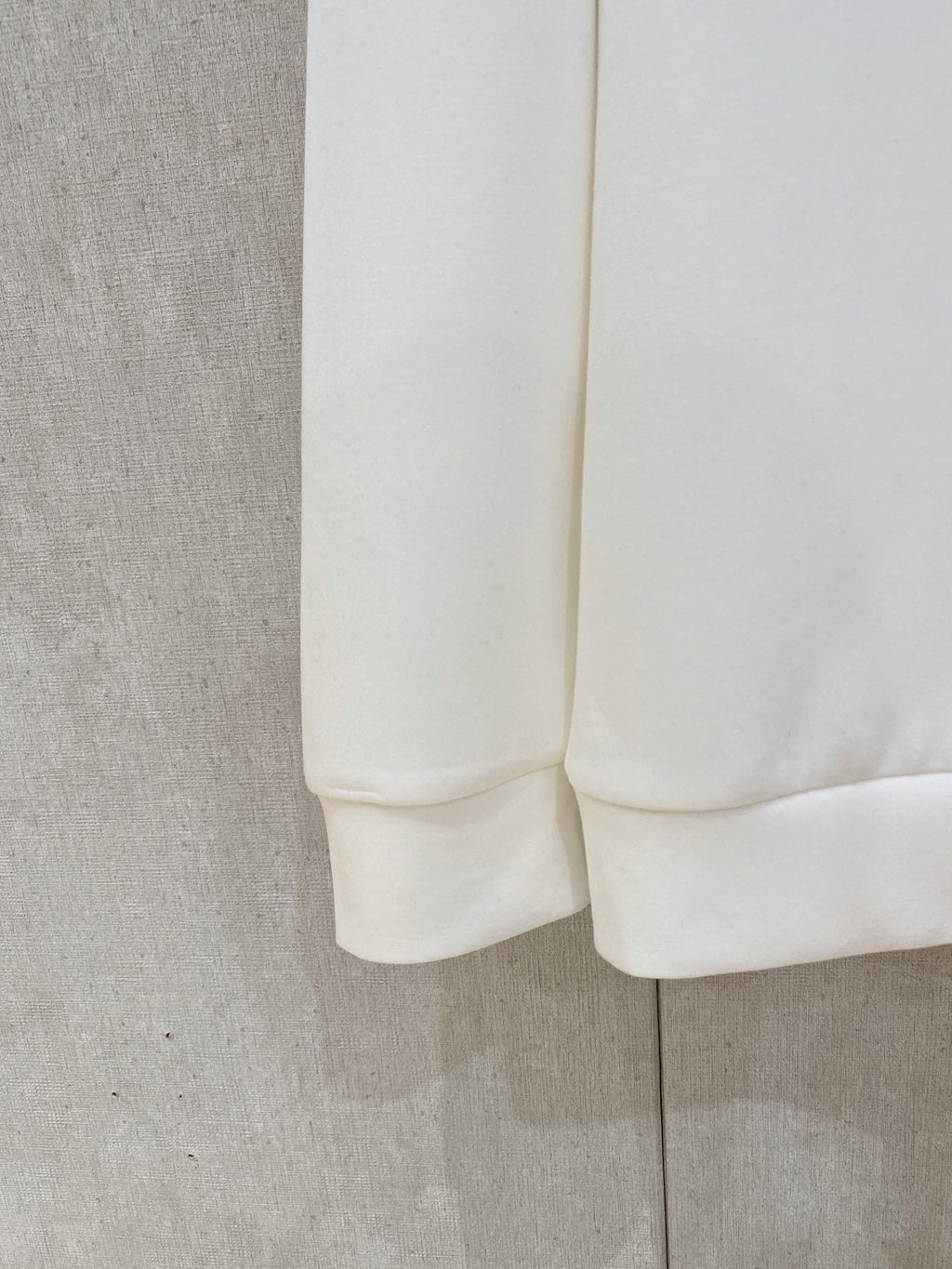 White sweatshirt fabric close-up showing cuff and rounded hem