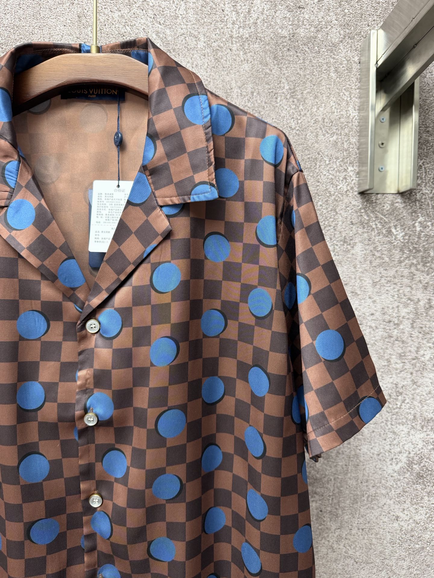 Brown short-sleeve shirt with blue dot check print, button placket, and fold-over collar