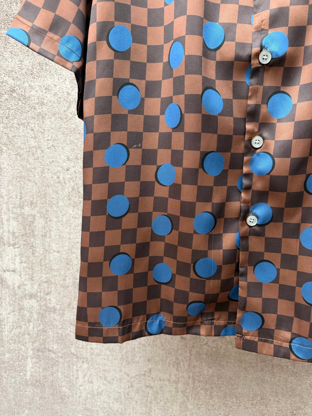 Brown short-sleeve shirt with blue circle and checker print, side buttons and hem