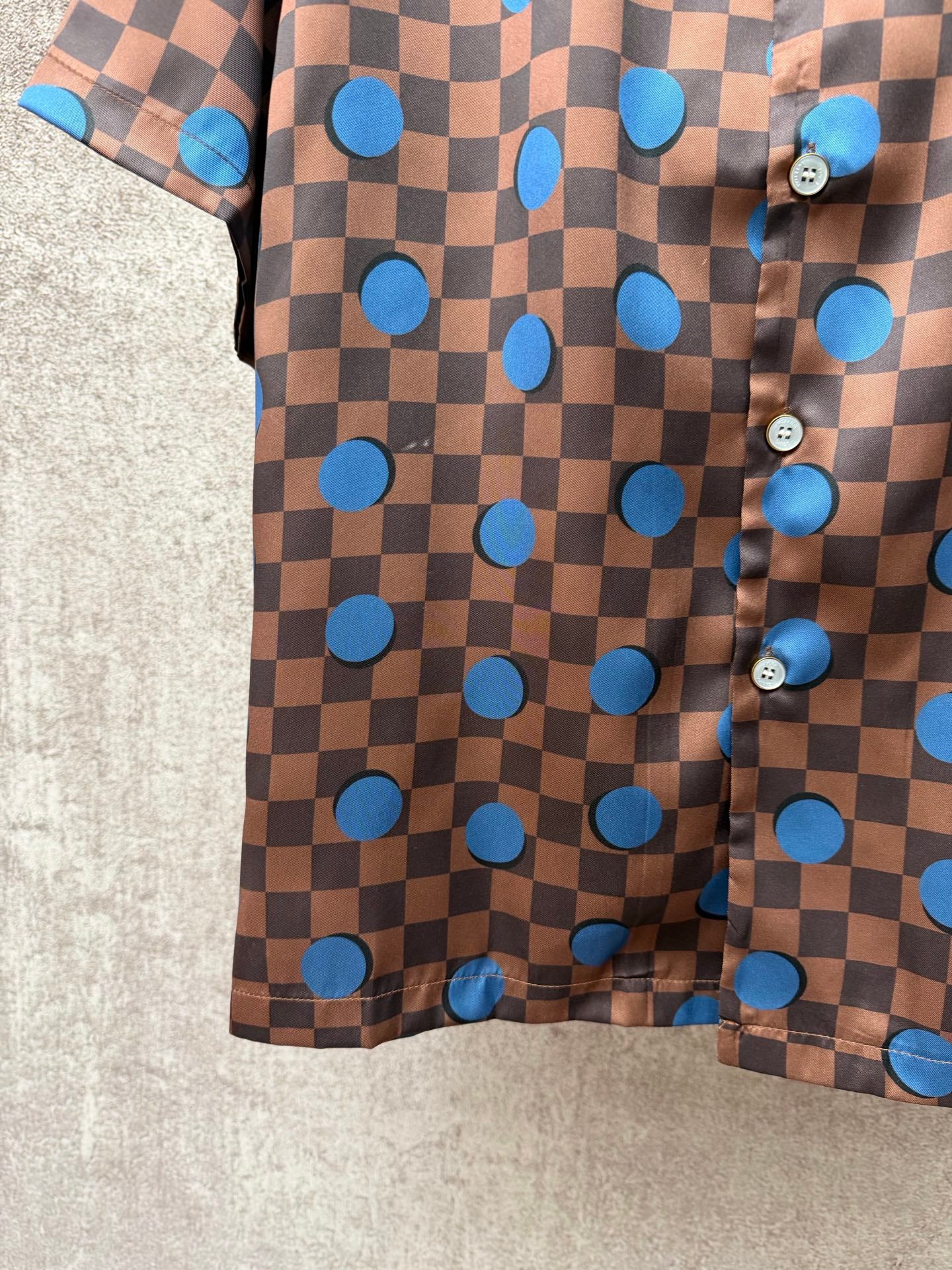 Brown short-sleeve shirt with blue circle and checker print, side buttons and hem