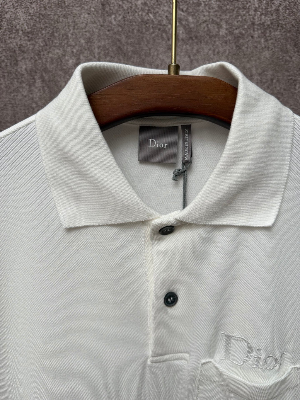 White Dior polo shirt close-up on collar, buttons, and embroidered chest logo