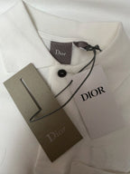 White Dior polo shirt with neck tag, Dior label, and product tags on fabric