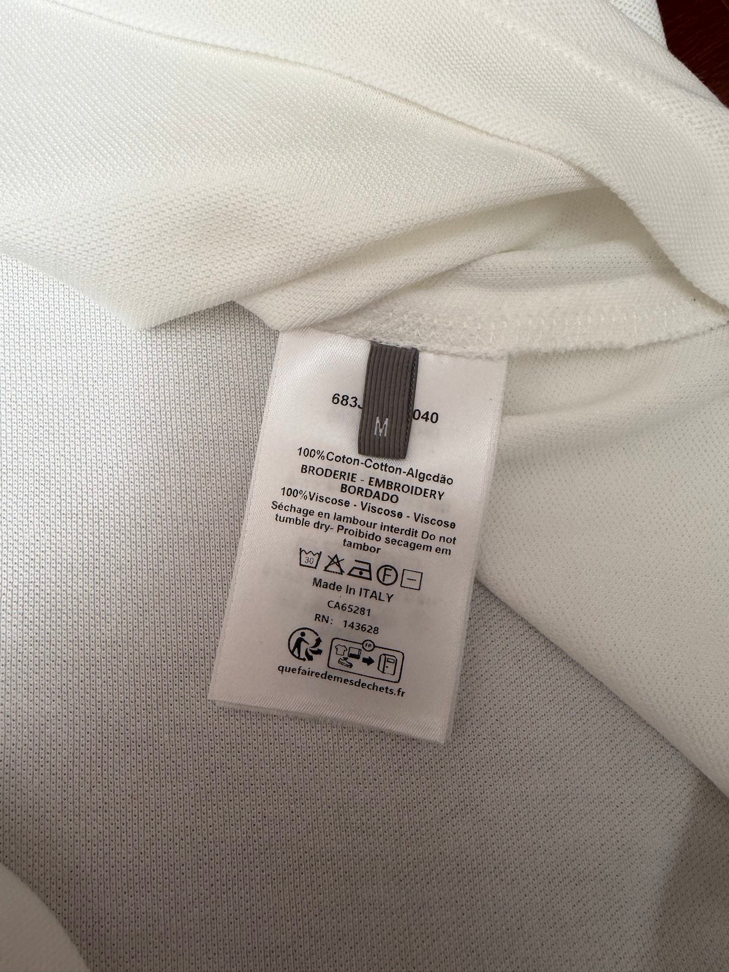 White polo shirt care label close-up with cotton and viscose fabric details