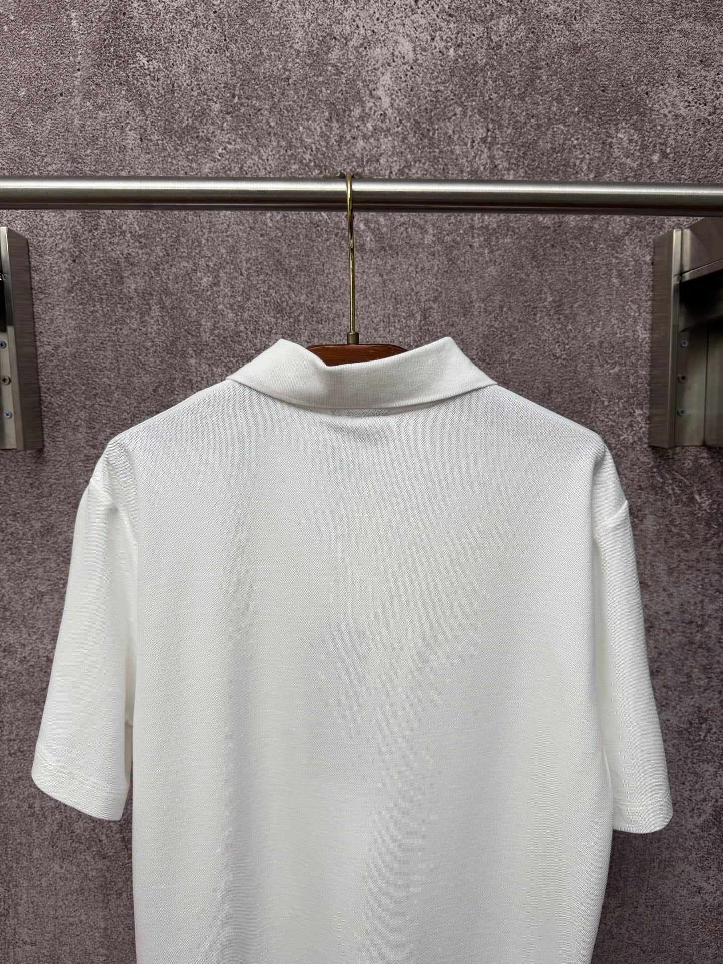 White Dior polo shirt back view on hanger with short sleeves and ribbed collar