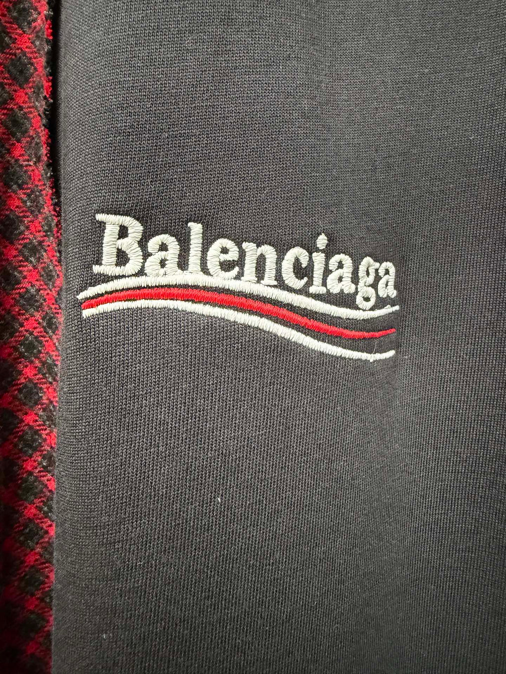 Balenciaga logo on dark gray chest panel of a red-and-black check shirt