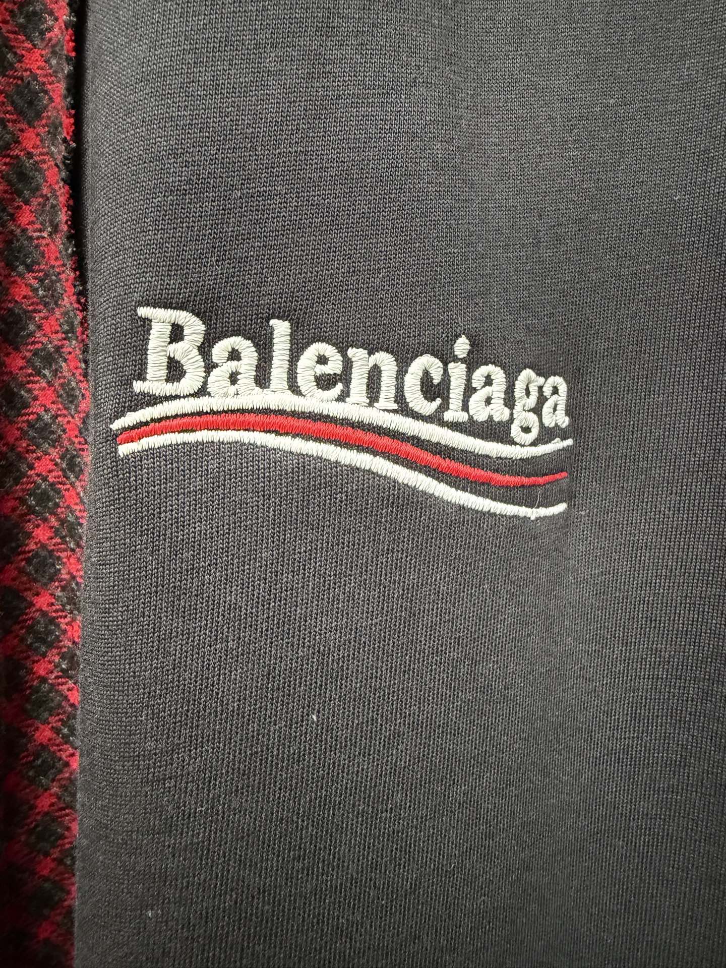 Balenciaga logo on dark gray chest panel of a red-and-black check shirt
