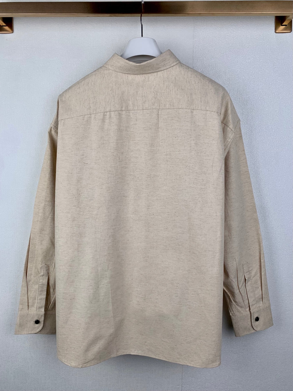 Beige long-sleeve button-up shirt back view with center seams and buttons
