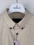 Beige long-sleeve button-up shirt collar with dark buttons and hanging tag