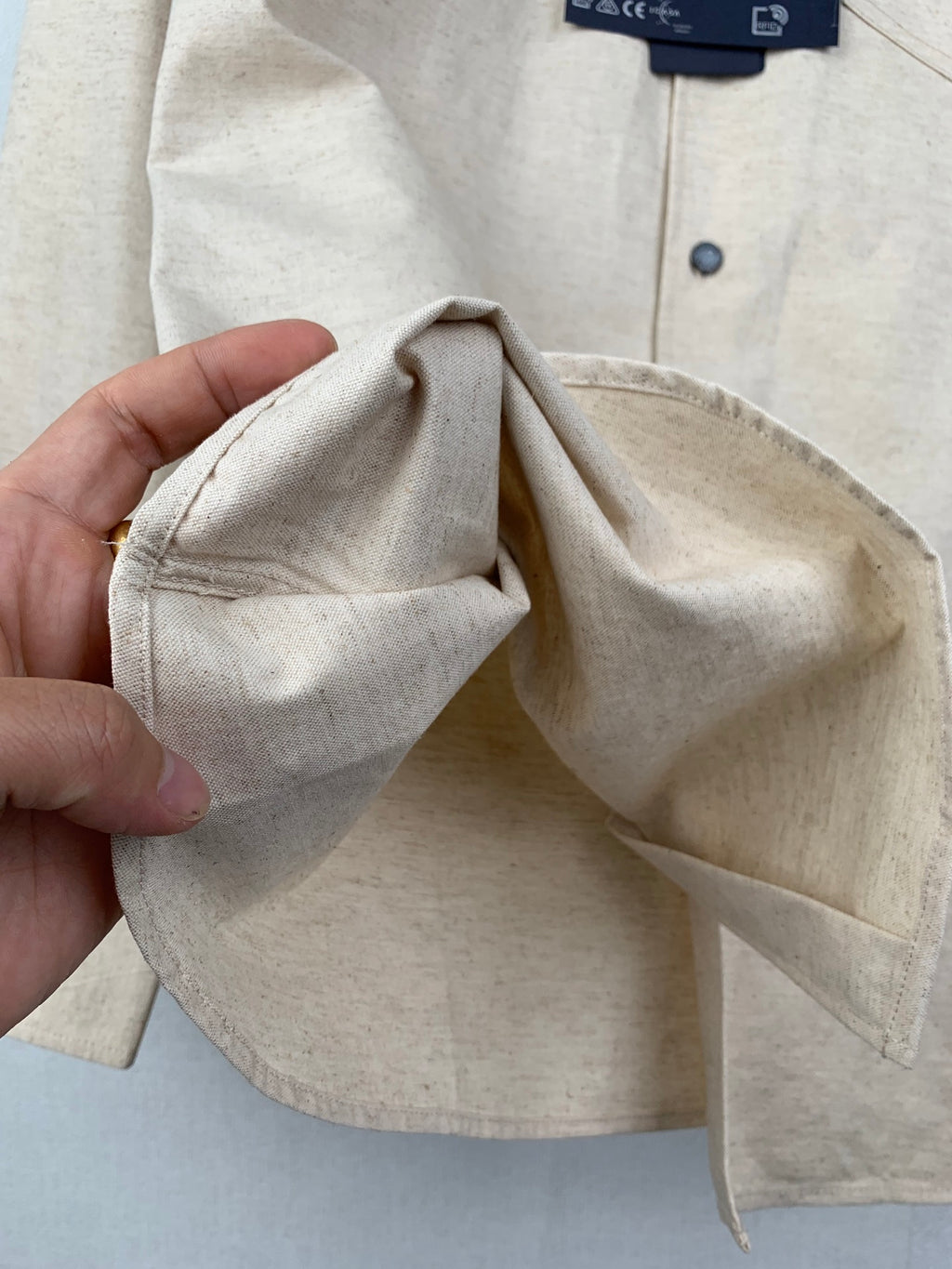 Beige shirt sleeve cuff with dark button and folded cuff edge detail