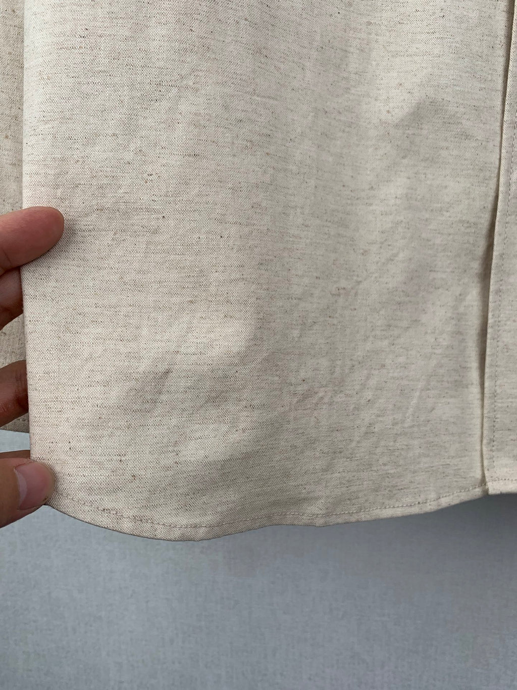 Beige shirt lower body and hem with visible stitching and texture