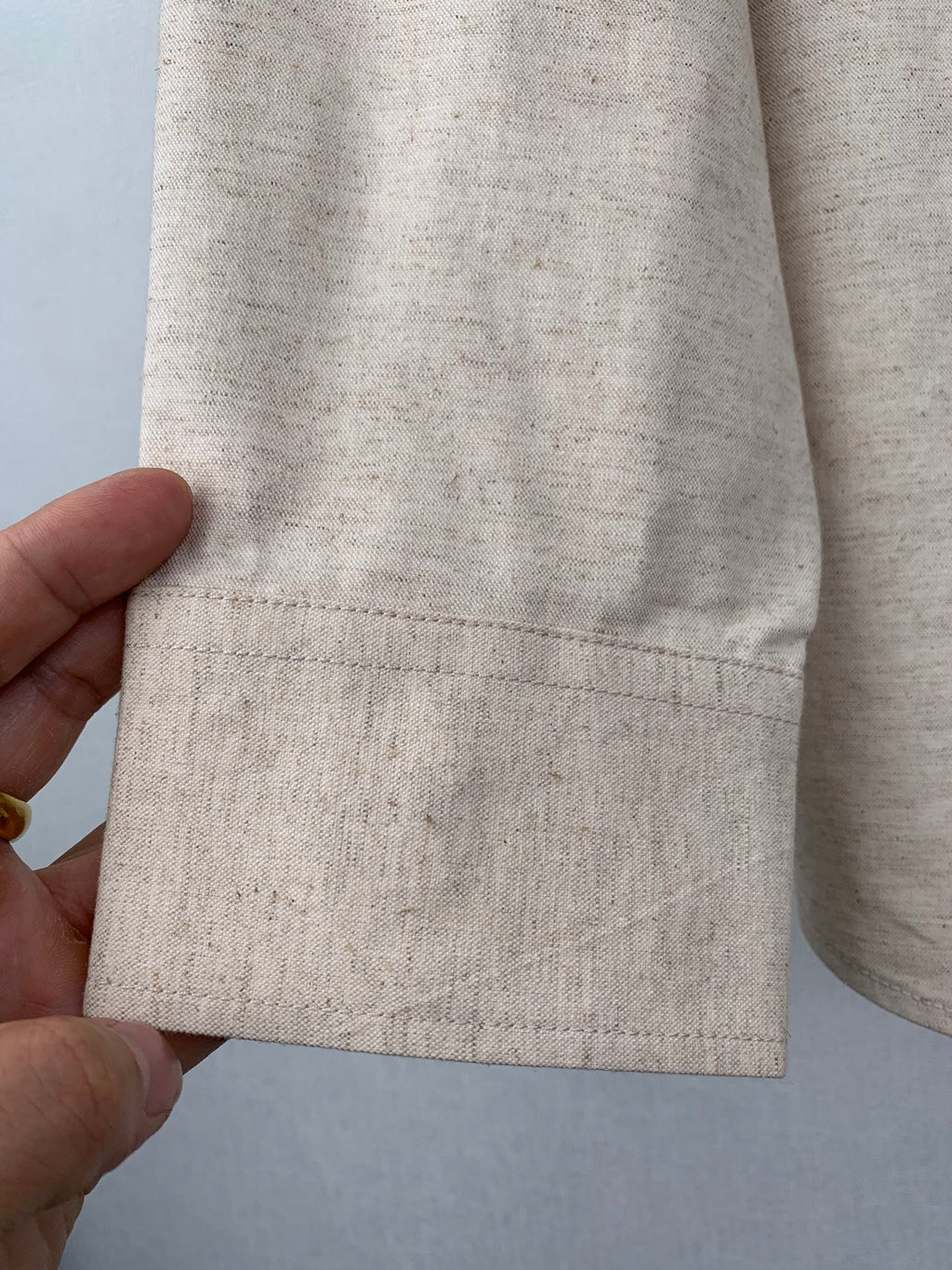 Beige shirt sleeve cuff and hem with dark button detail