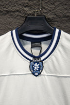 Balenciaga T-shirt neckline close-up with blue emblem patch and ribbed trim