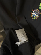 Black T-shirt sleeve with care label and small embroidered crest