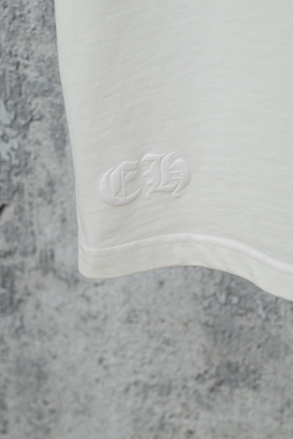 White T-shirt hem with subtle circular logo emboss