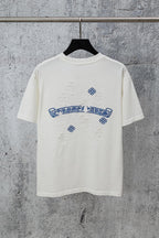 White graphic T-shirt with blue embroidered-style logo and small cross-like accents