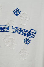 White T-shirt close-up of blue logo print and small cross-like raised embroidery