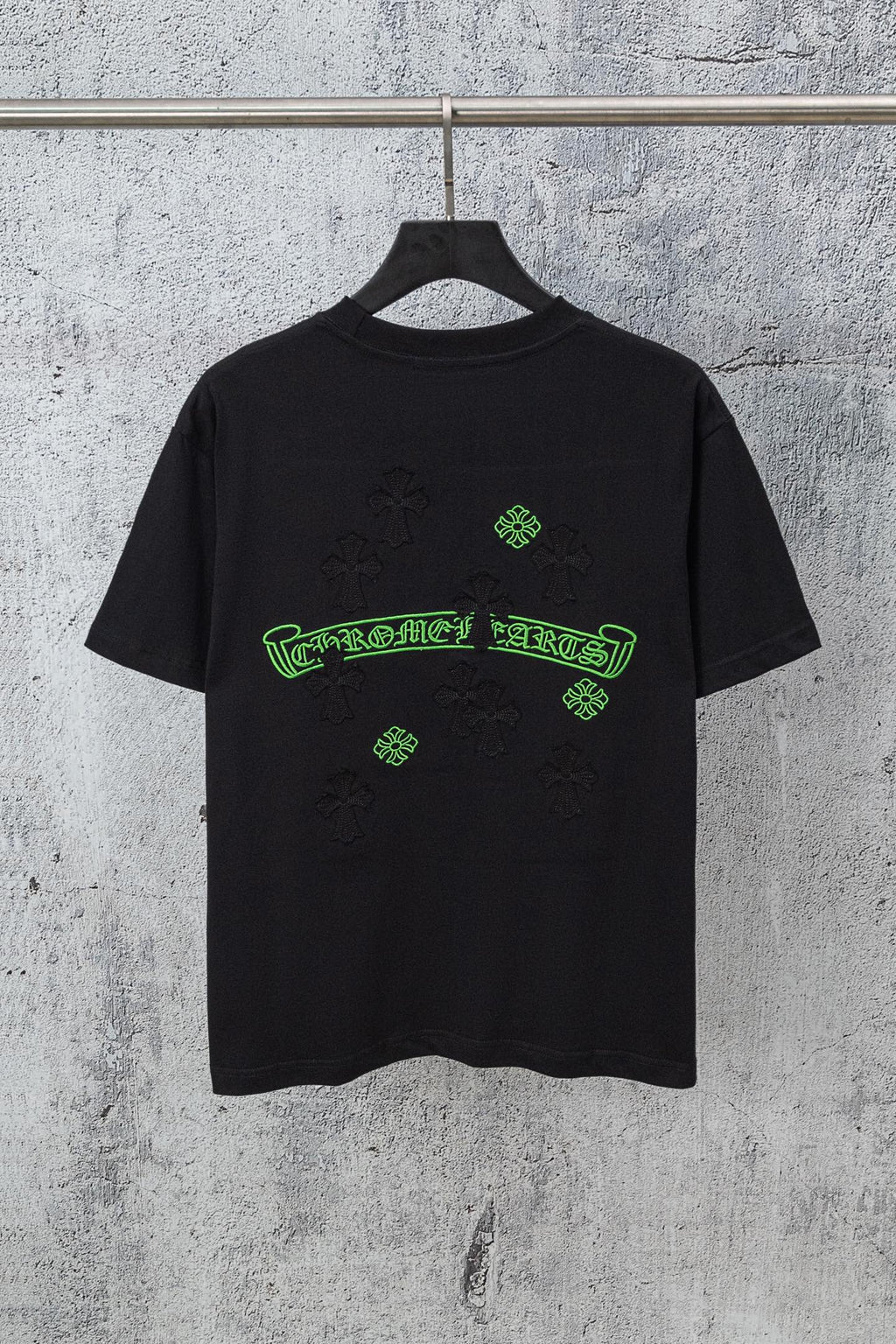 Black graphic T-shirt with green logo print and small cross-like pattern details