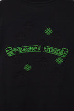 Black T-shirt close-up of green logo outline and small cross-like embroidery pattern