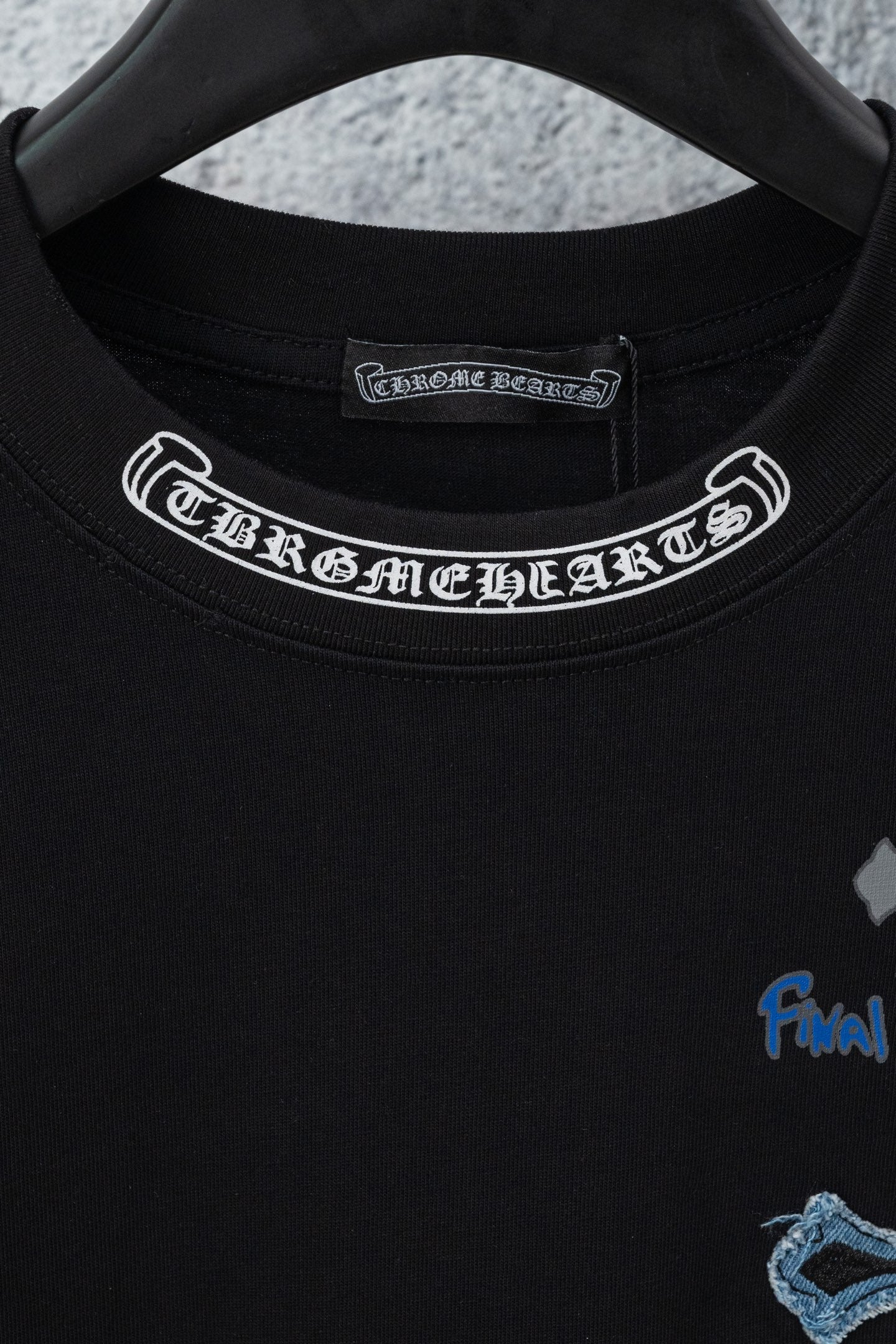 Black crew-neck T-shirt with white printed collar band and partial chest graphic