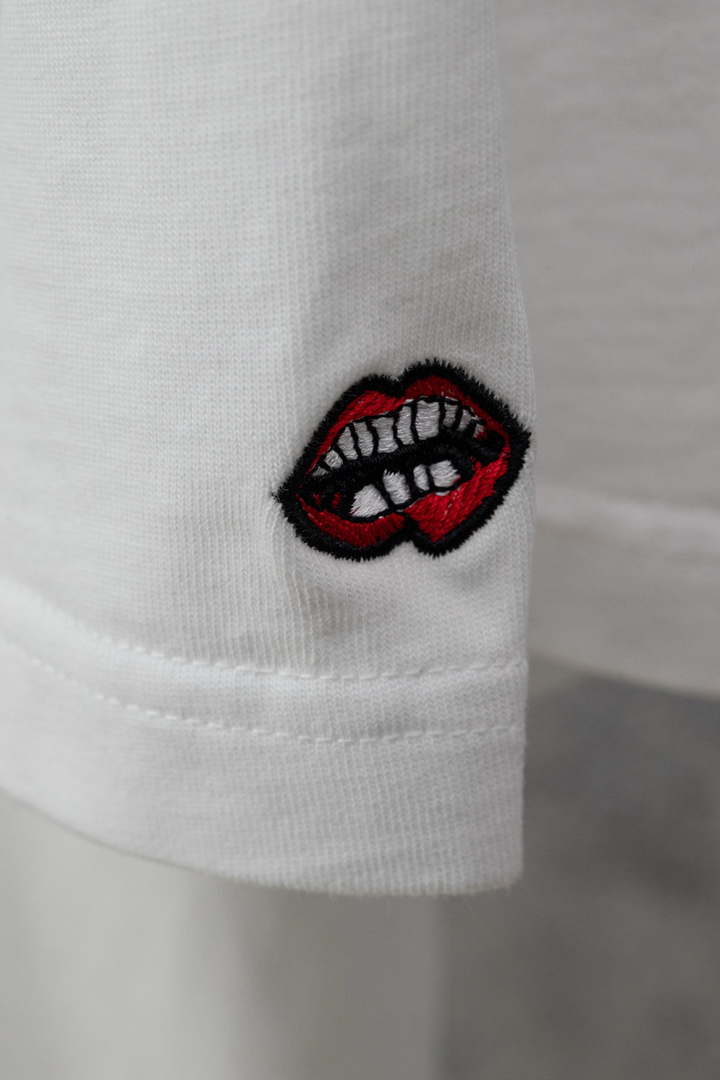 White short-sleeve T-shirt sleeve with embroidered red lips patch