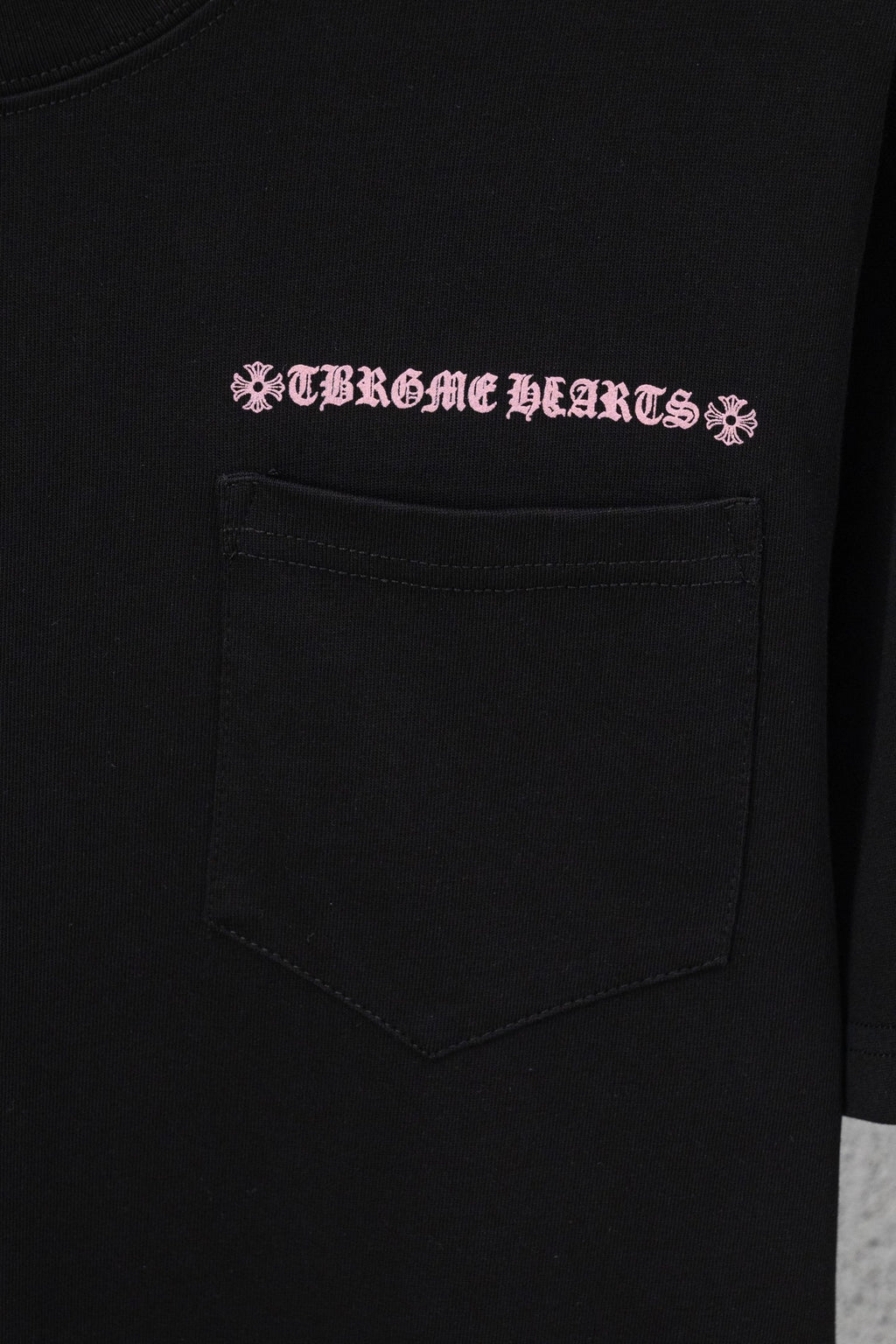 Black short-sleeve T-shirt with pink graphic text and front chest pocket