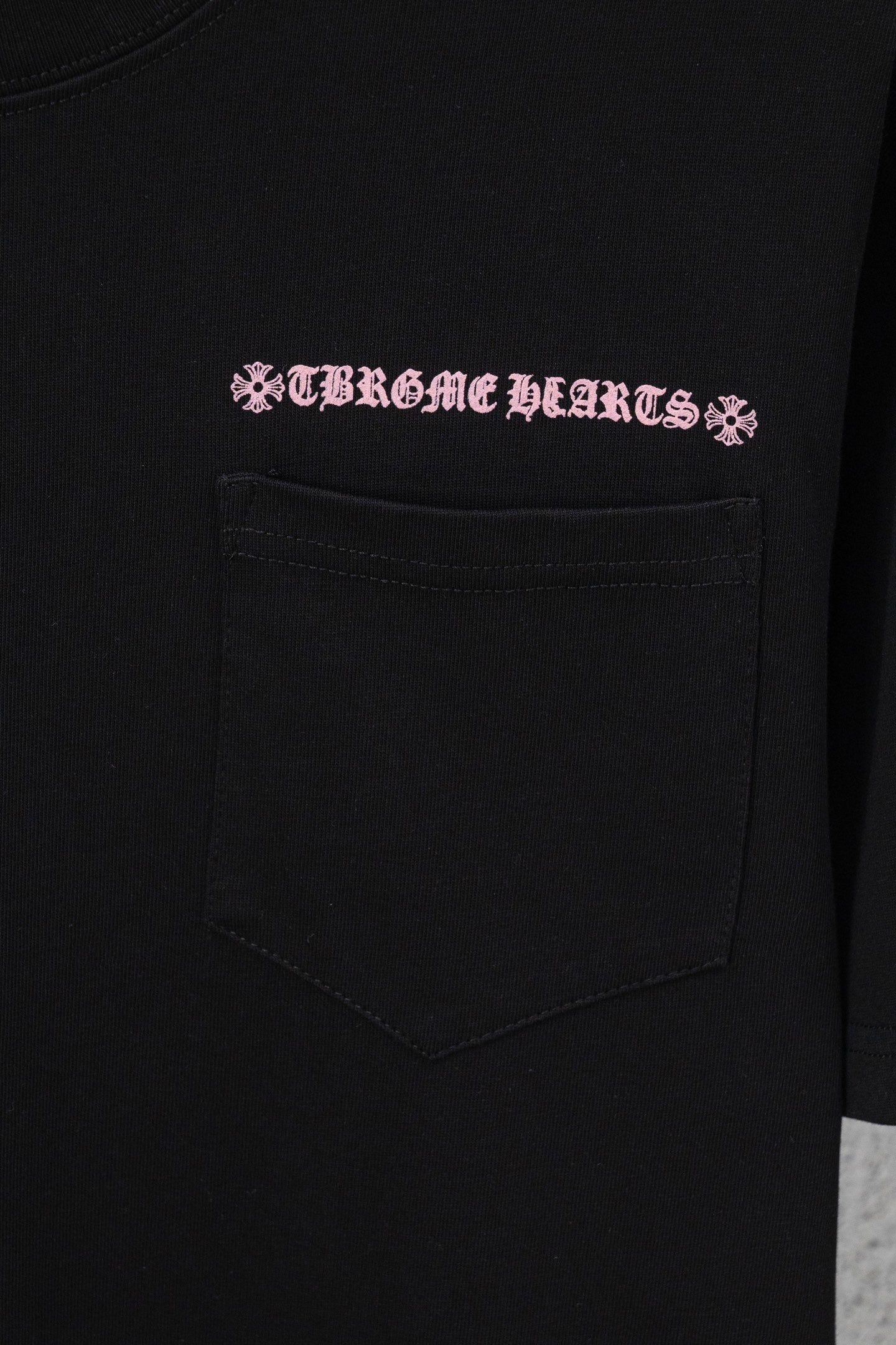Black short-sleeve T-shirt with pink graphic text and front chest pocket