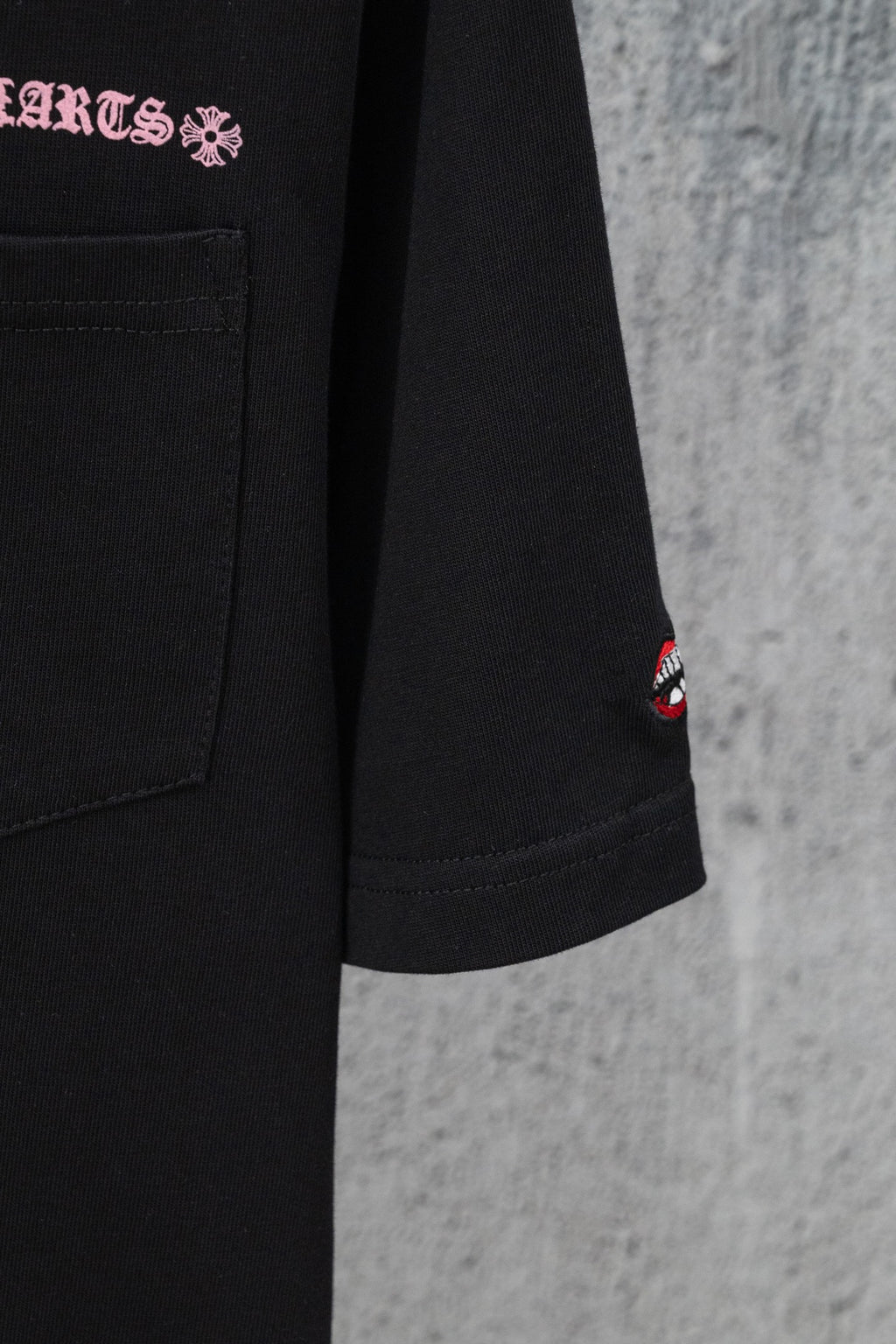 Black short-sleeve T-shirt with chest pocket and small red lips logo