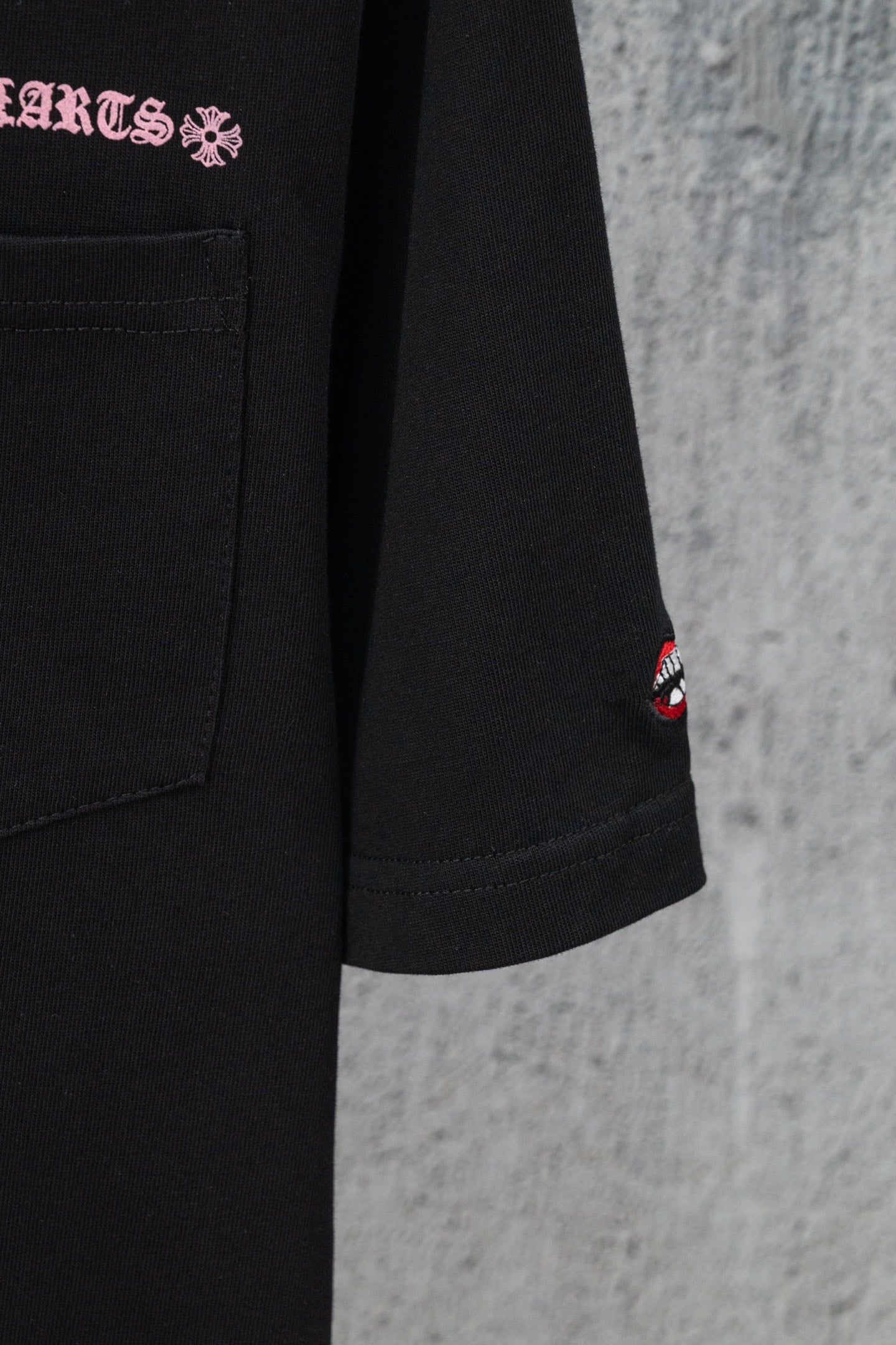 Black short-sleeve T-shirt with chest pocket and small red lips logo