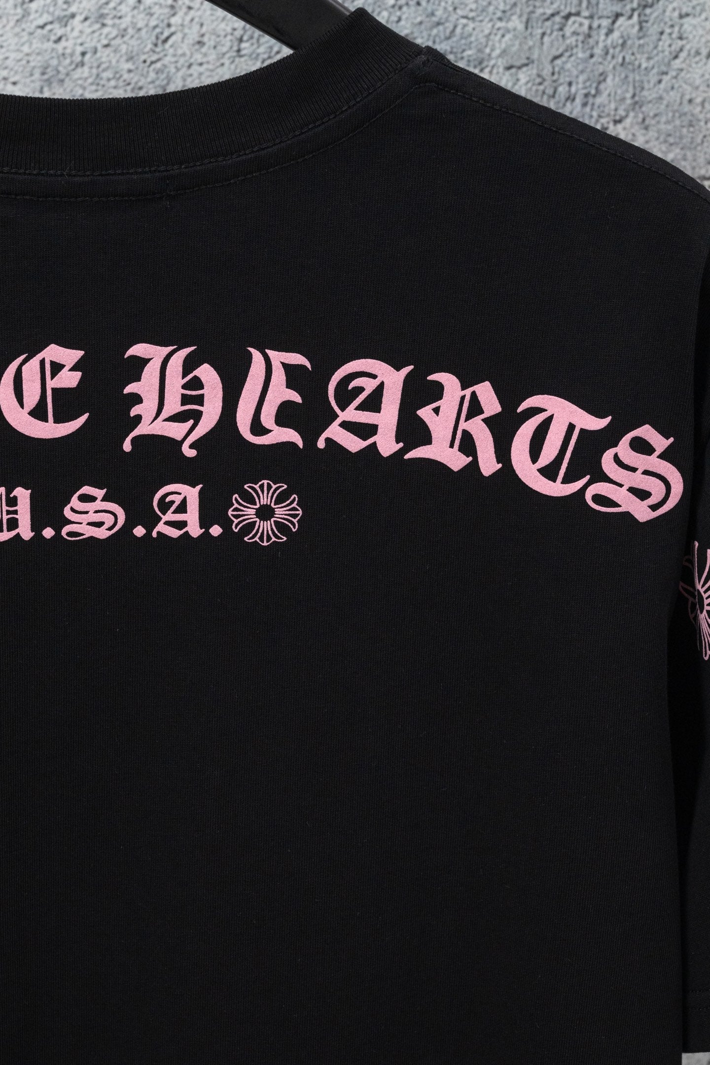 Black short-sleeve T-shirt with large pink front graphic lettering