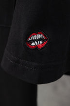 Black short-sleeve T-shirt with embroidered red-and-white lip patch on sleeve