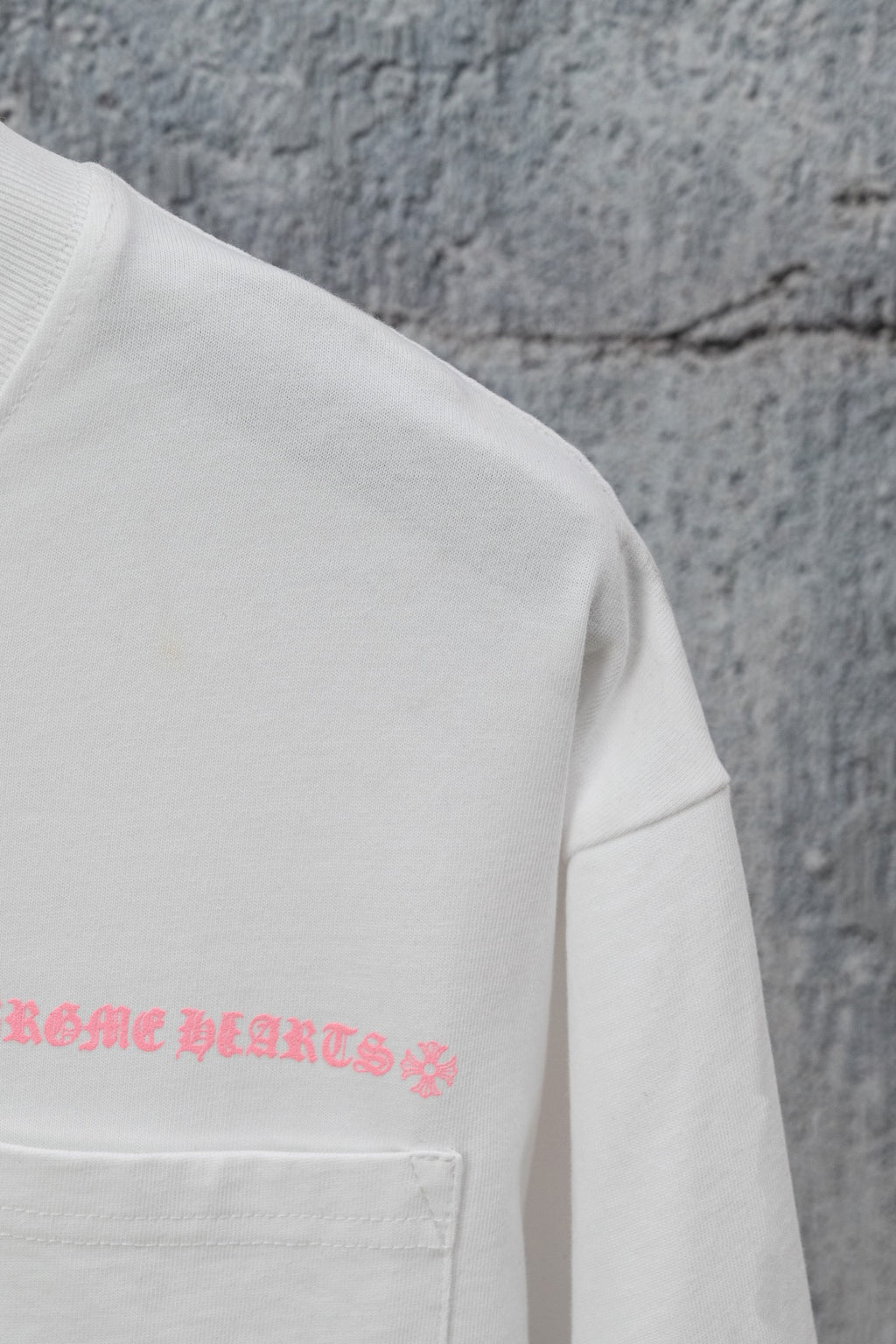 White short-sleeve T-shirt with pink graphic text near the chest pocket