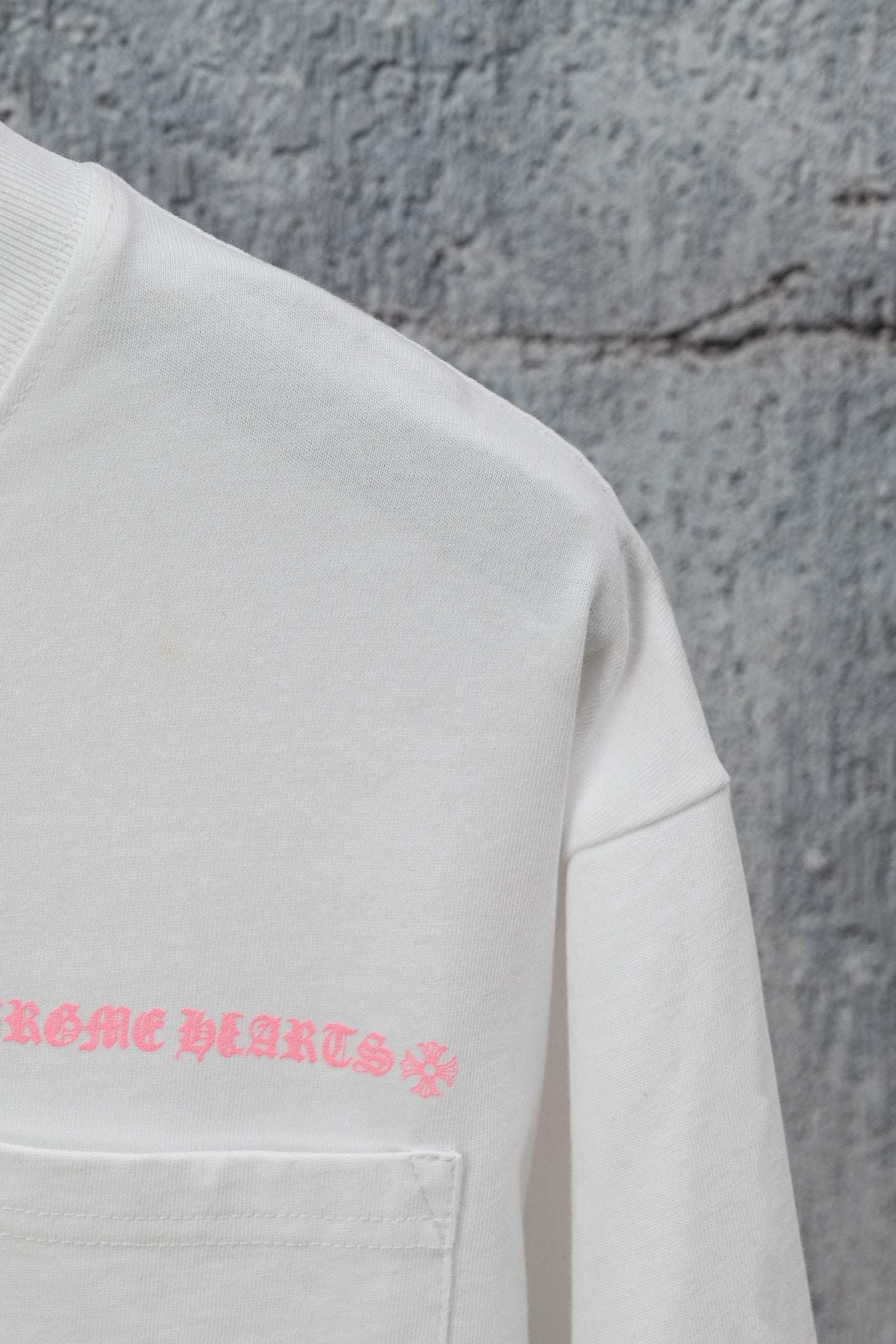 White short-sleeve T-shirt with pink graphic text near the chest pocket