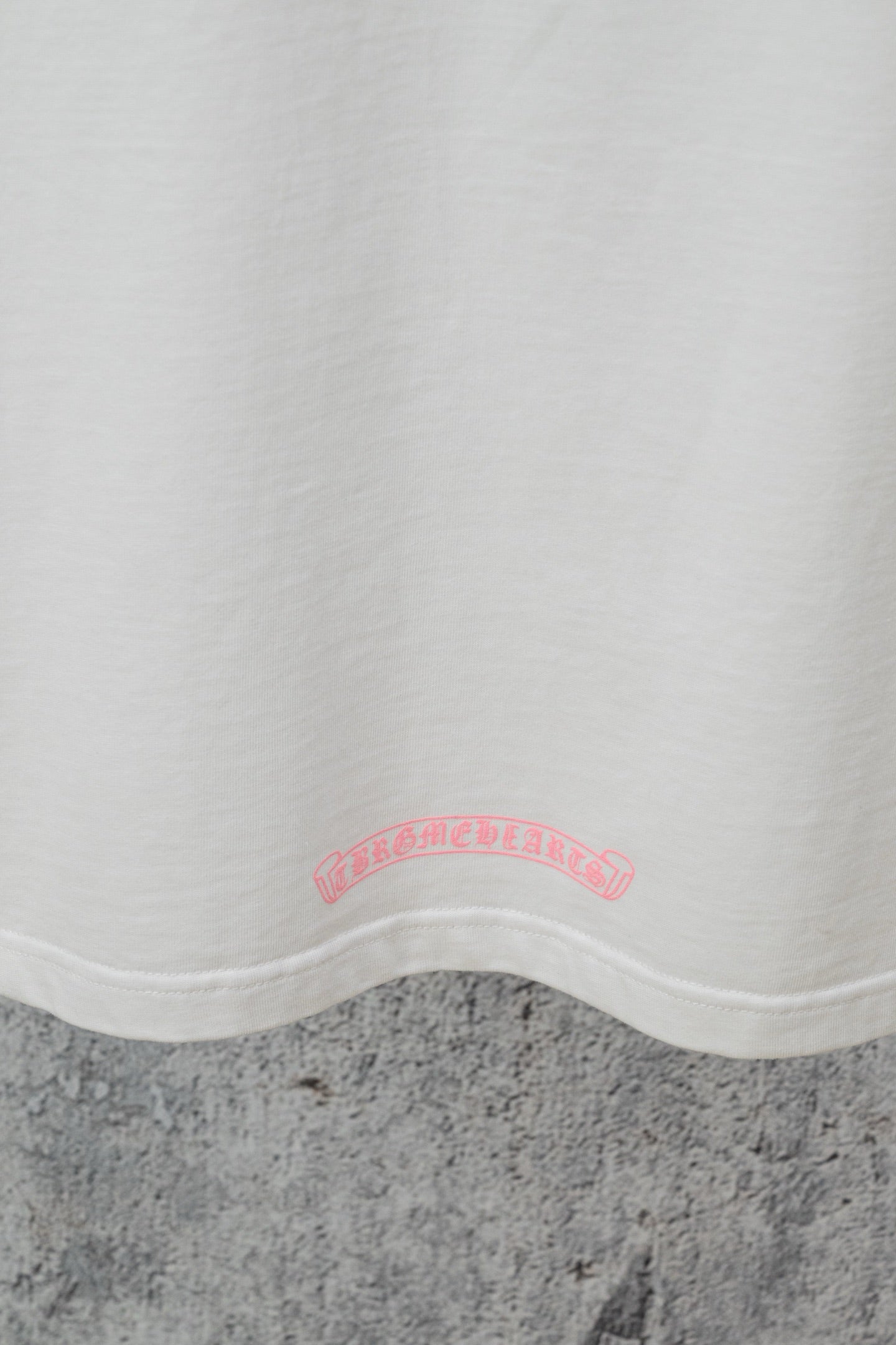 White short-sleeve T-shirt hem with small faded pink logo print
