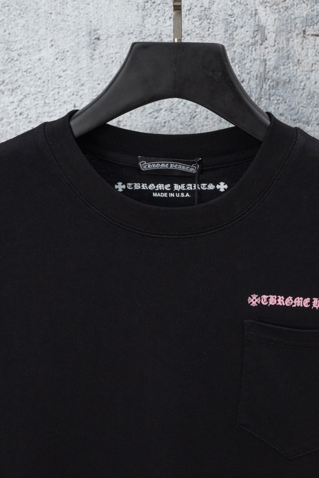 Black short-sleeve T-shirt close-up with neckline text and chest pocket logo
