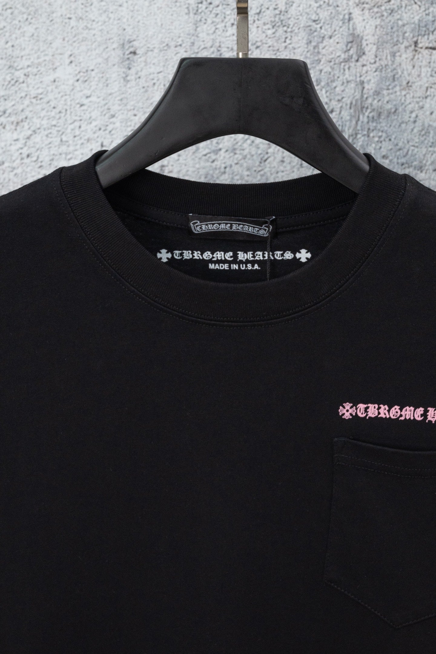 Black short-sleeve T-shirt close-up with neckline text and chest pocket logo