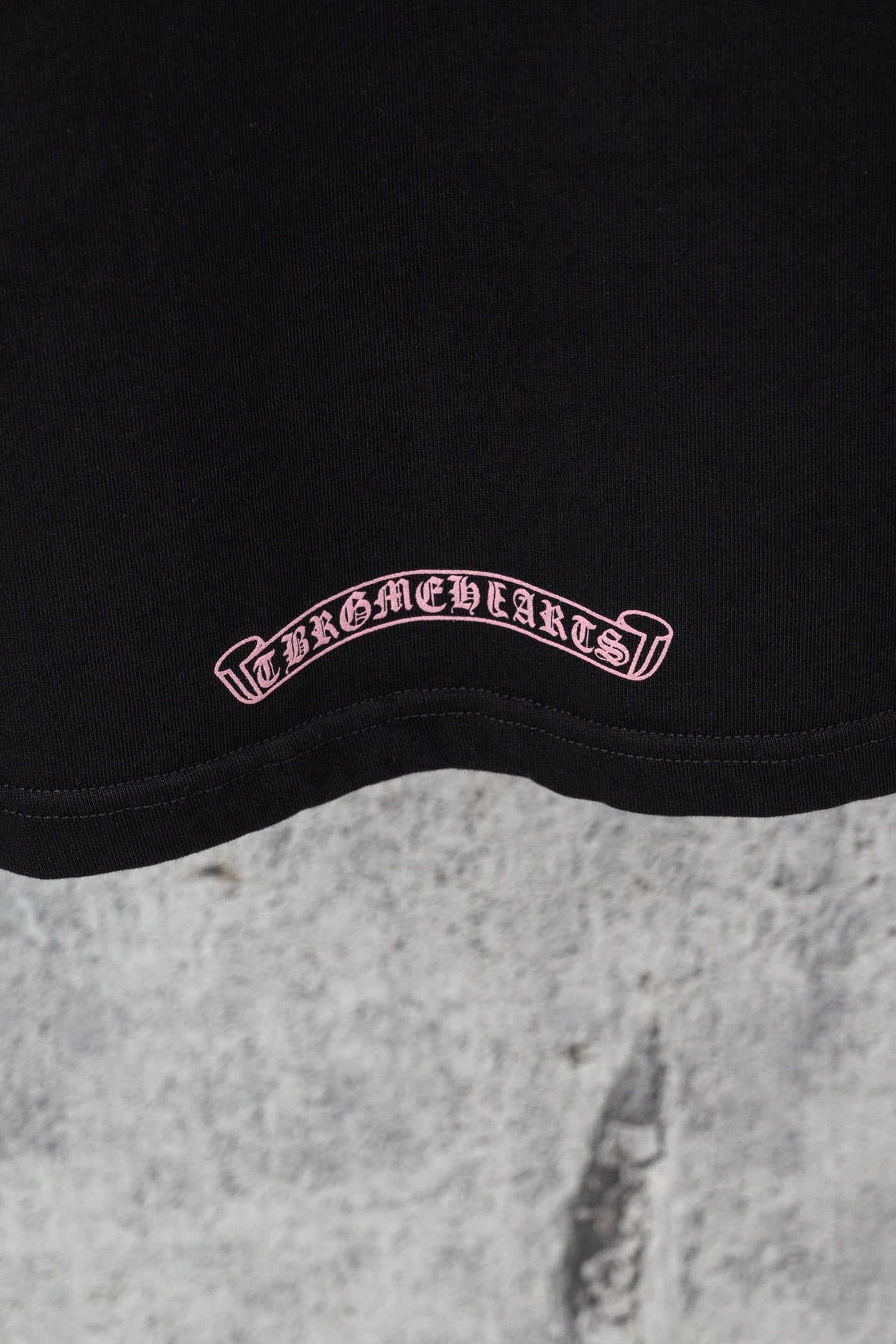 Black short-sleeve T-shirt logo patch near hem in pink