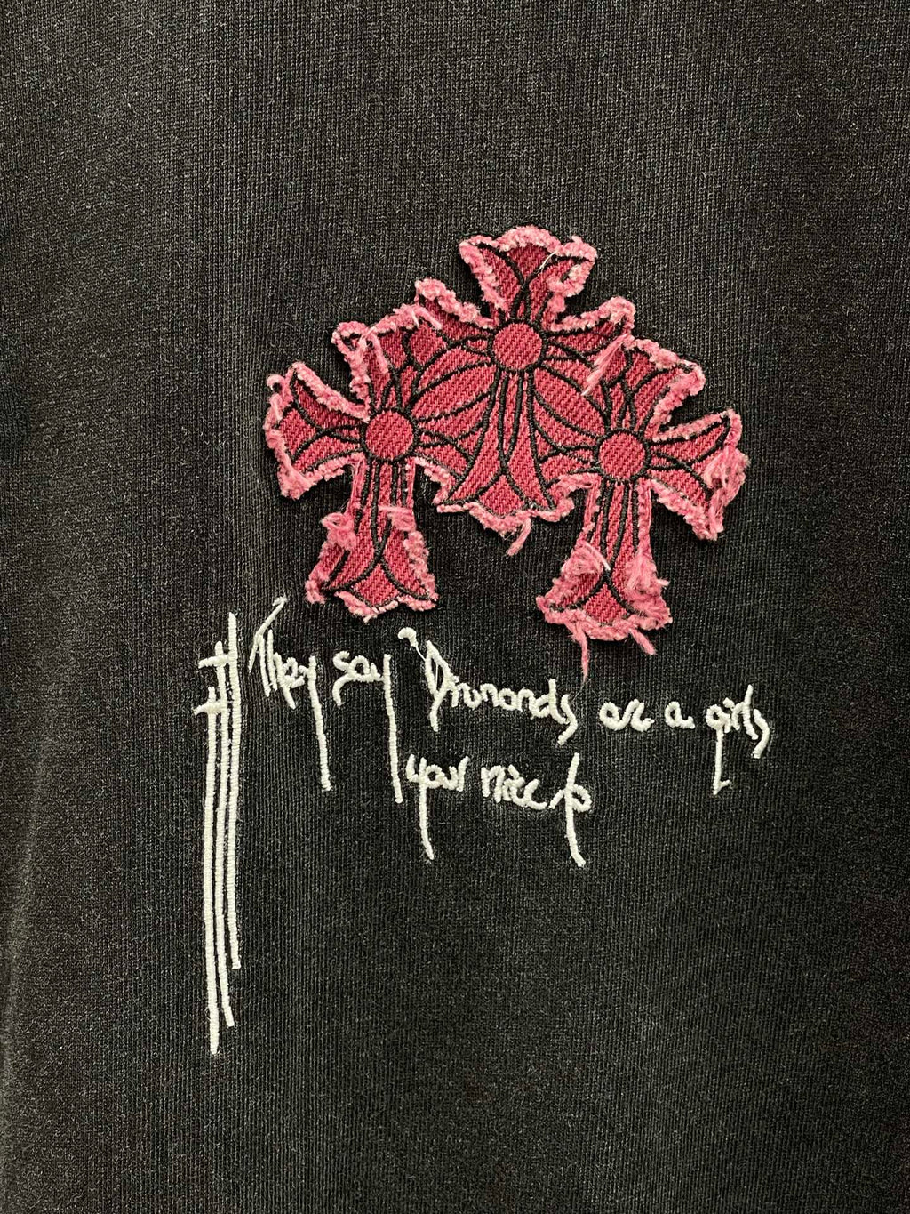 Short-sleeve T-shirt close-up of pink cross embroidery with white script details
