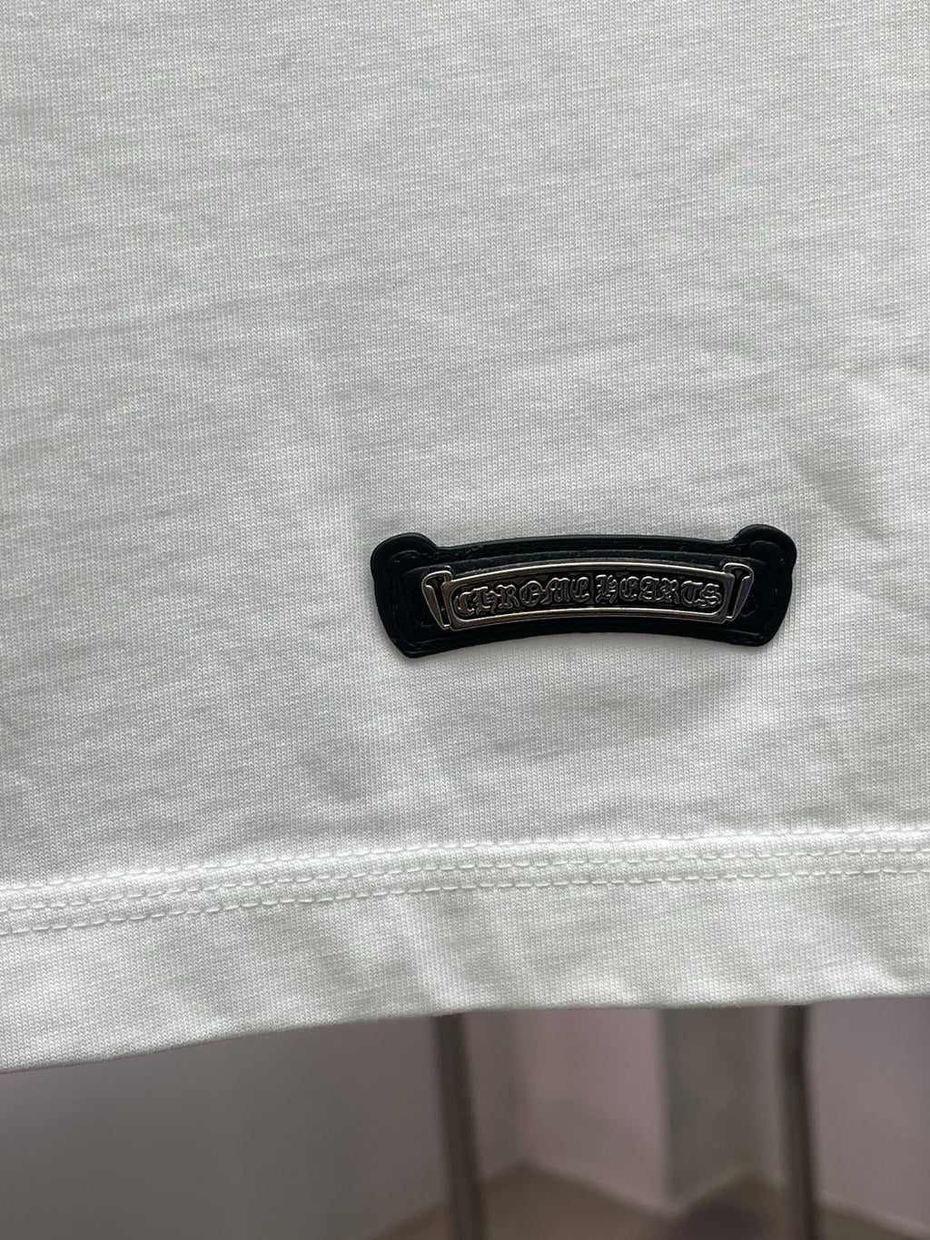 White T-shirt hem with black embroidered brand label and stitched bottom edge