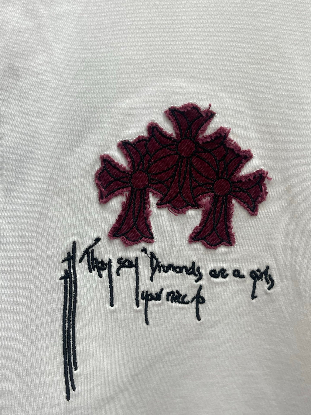 White T-shirt chest graphic: maroon flower shapes with black script lettering
