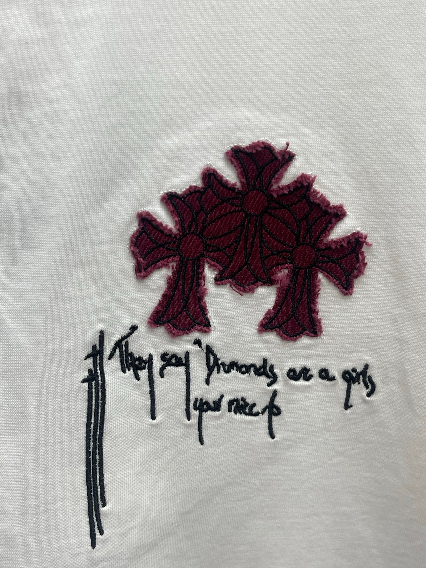 White T-shirt chest graphic: maroon flower shapes with black script lettering